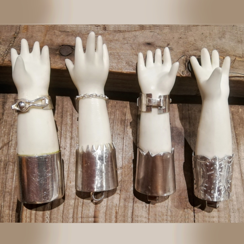 Four little porcelain hands in a row with various silver attachments which make them into jewellery
