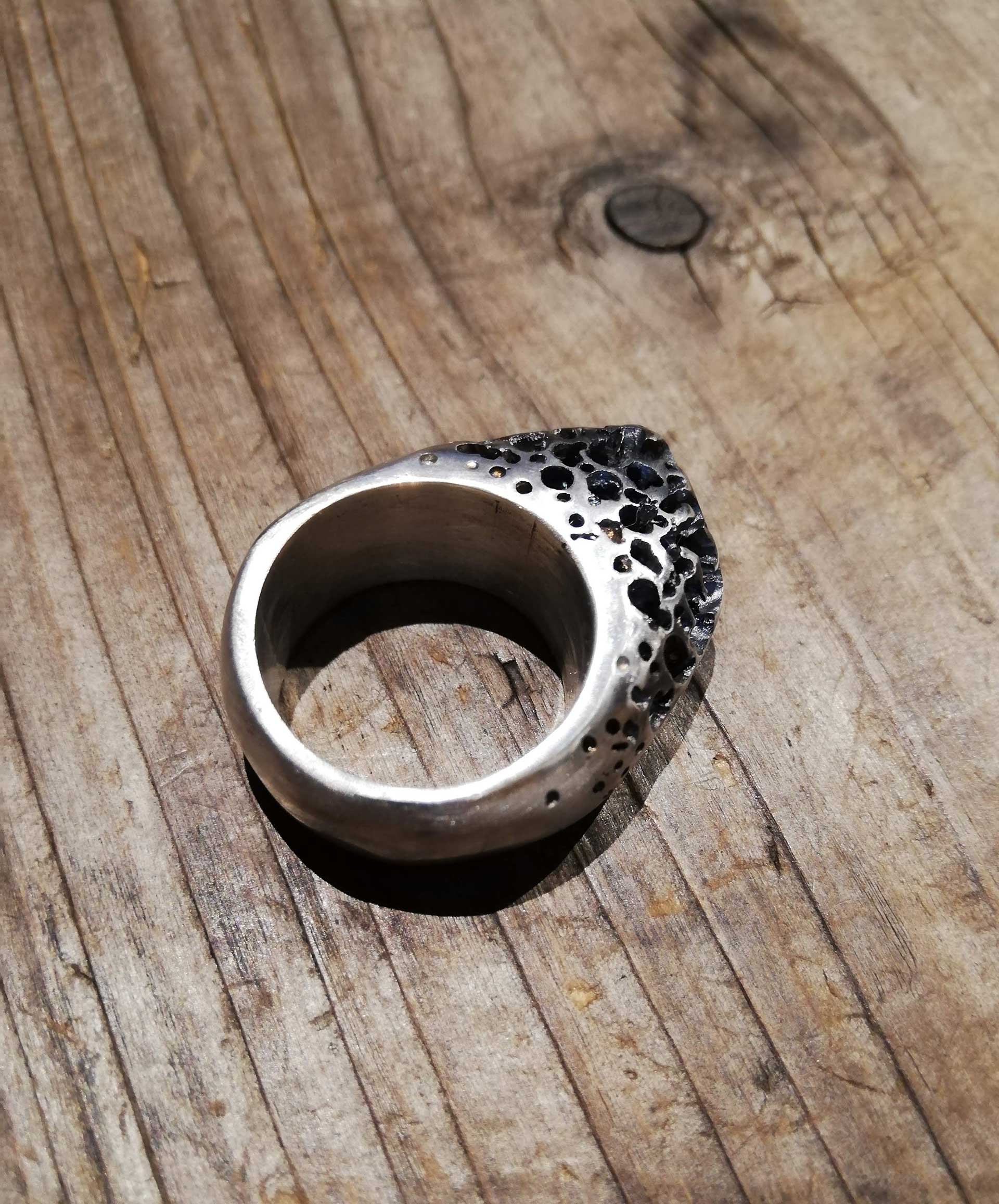 The image shows a silver ring with many holes drilled out of it